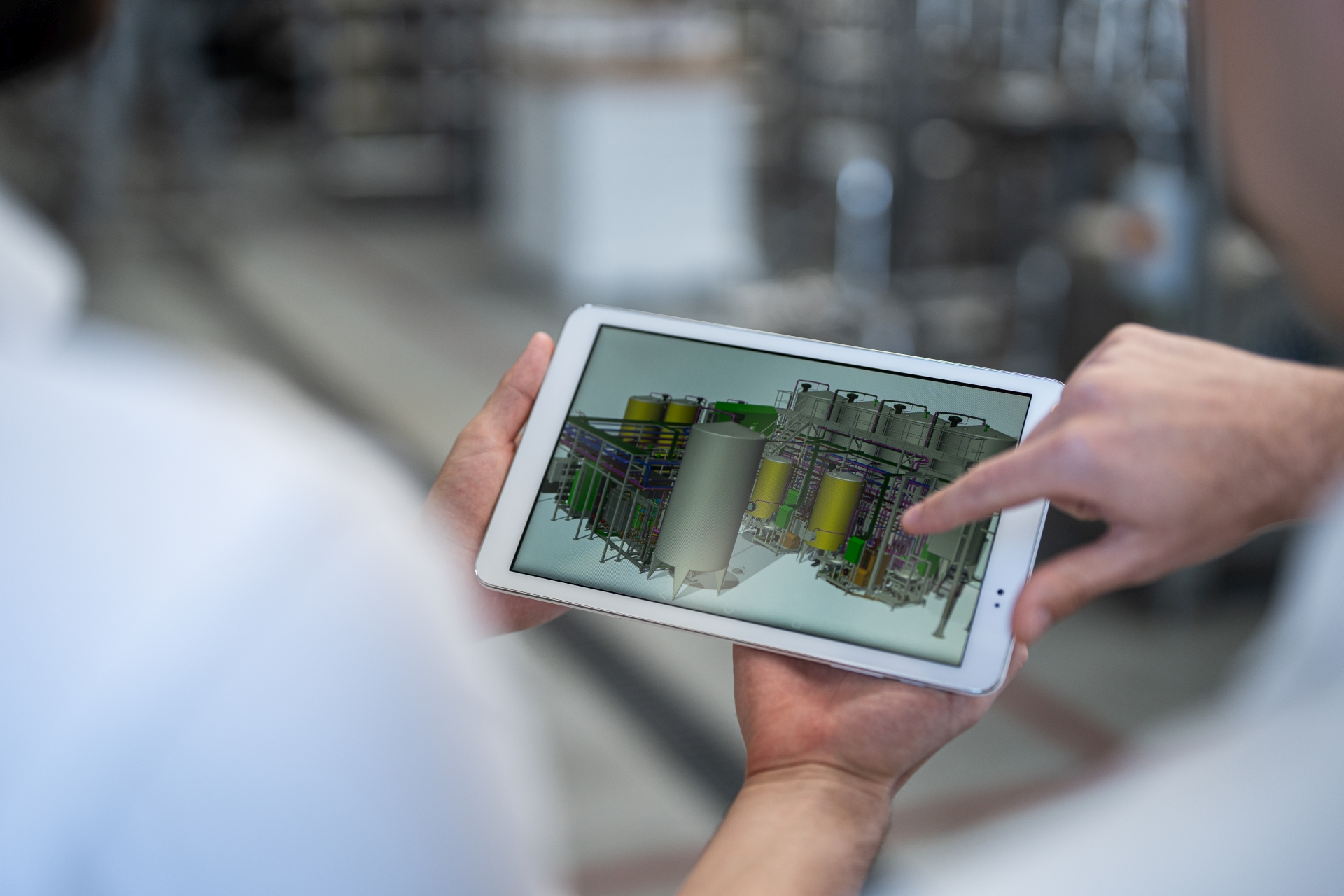 Photo engineer with tablet showing tank farm planning, realised process plant in the background